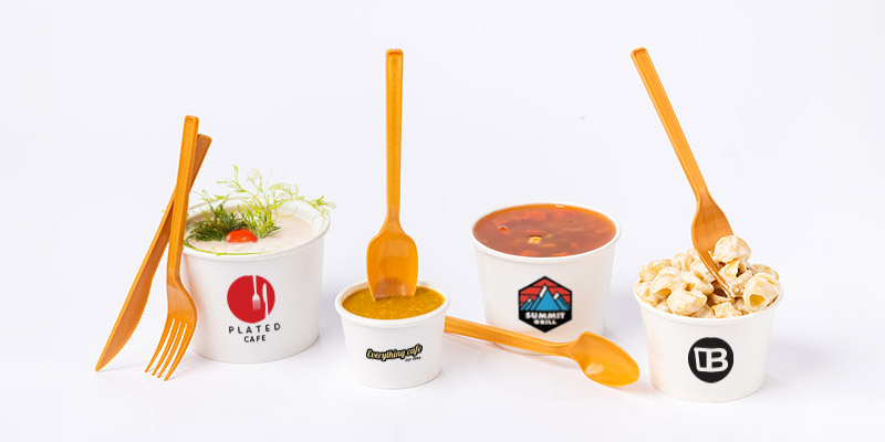 A line of 4 custom printed soup cups filled with 3 soups and 1 pasta salad.